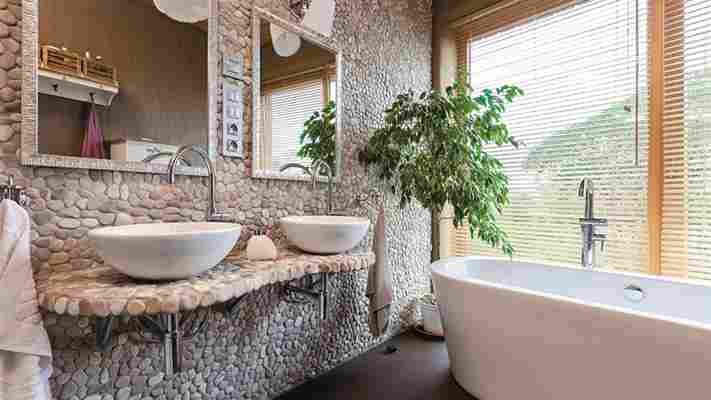 Moderní koupelnu zdobí stěna obložená oblázky, majitelé ji vyrobili sami
